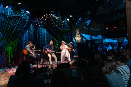 Charles Esten, Matthew Ramsey, and Lauren Alaina on stage performing for caregivers