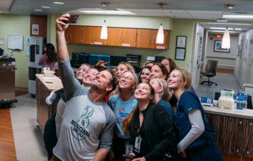 Charles Esten poses taking a selfie with caregivers